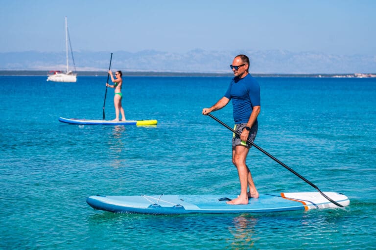 Couple riding SUP stand up paddle on vacation