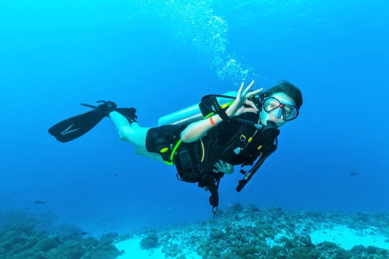 Female scuba diver underwater showing signal — Plongée