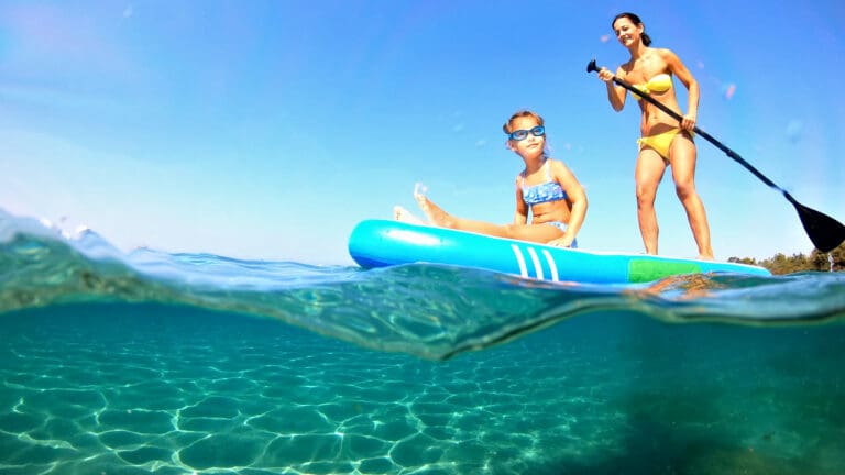 Mom and daughter paddleboard on a sunny day