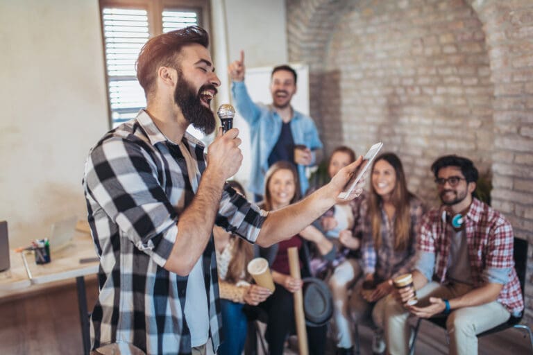 Business people singing karaoke in modern office
